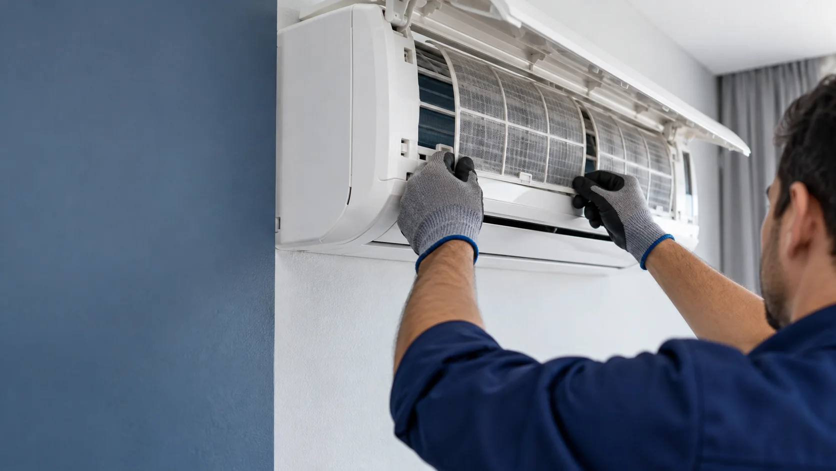 Técnico de uniforme azul inspecionando os filtros de um split